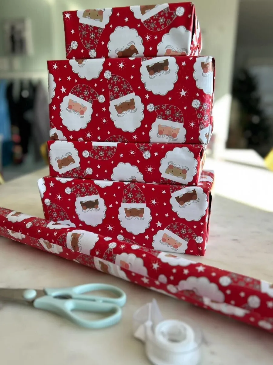 Wrapping paper, scissors and tape laid out beside wrapped gifts
