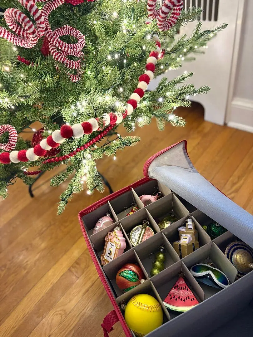 An ornament storage box with compartments, open beside a decorated tree