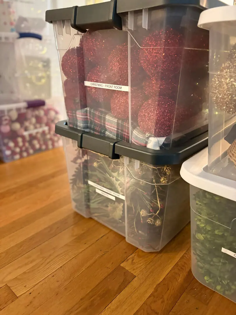 Clear totes of red ornaments stacked and ready for storage