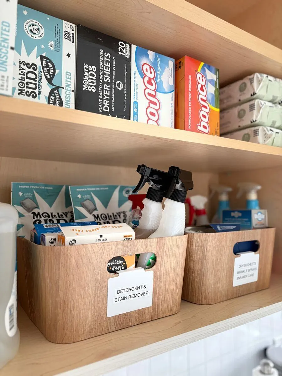 Laundry supplies in labeled wood-look bins below dryer sheets