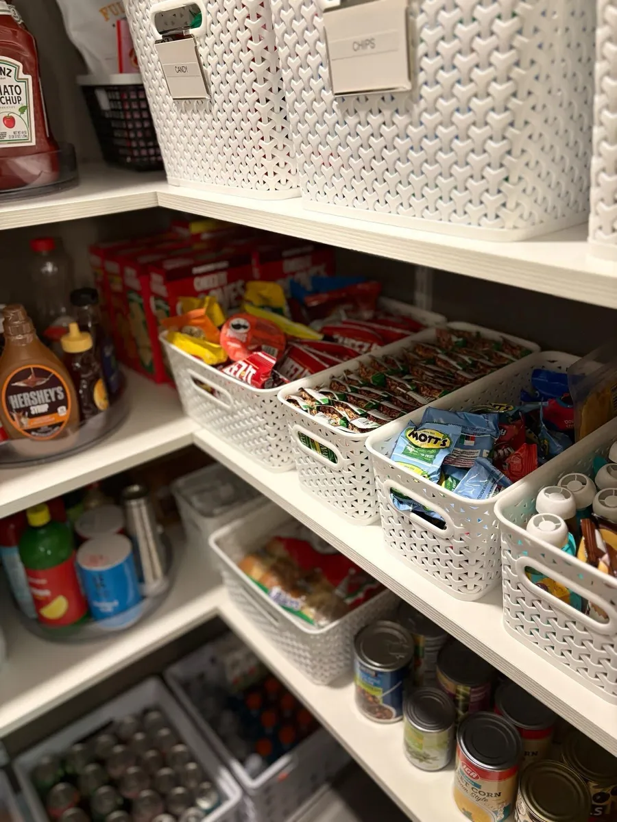 Snacks sorted into white baskets on pantry shelves