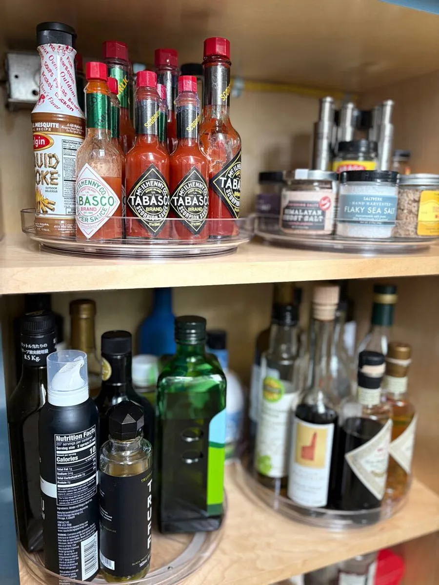 Hot sauces, salts and oils on clear turntables in a cabinet