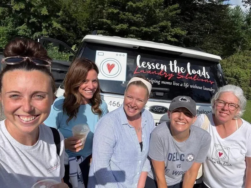 Five Lessen the Loads specialists standing together in front of a branded company van