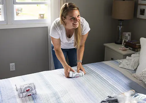 A Lessen the Loads employee folding laundry on top of a bed in a residential home